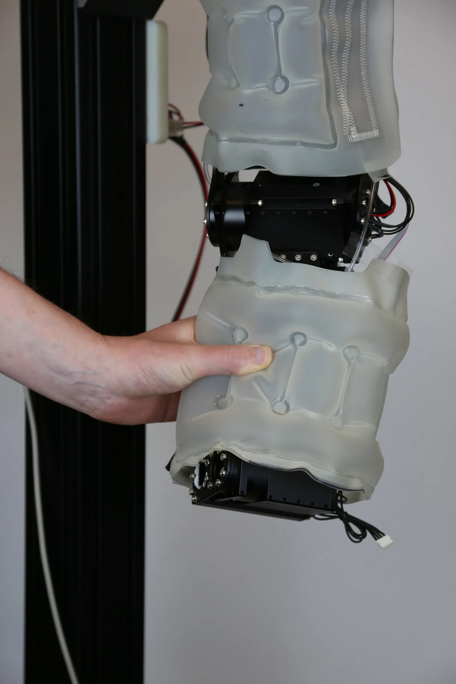 Image showing a hand squeeze the "forearm" of a robot arm that has been equipped with an airbubble.